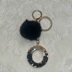 Bag charm or keychain with pom pom. Colors are black and gold